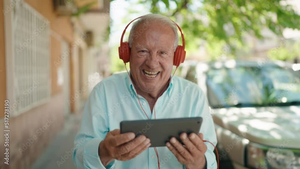 Senior grey-haired man smiling confident watching video on touchpad at street Senior grey-haired man smiling confident watching video on touchpad at street