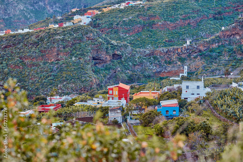 Architectural colorful buildings of a small hidden town in the mountains. The landscape of a colorful village on the outskirts of nature near a hill. Scenic view of bright buildings near foliage