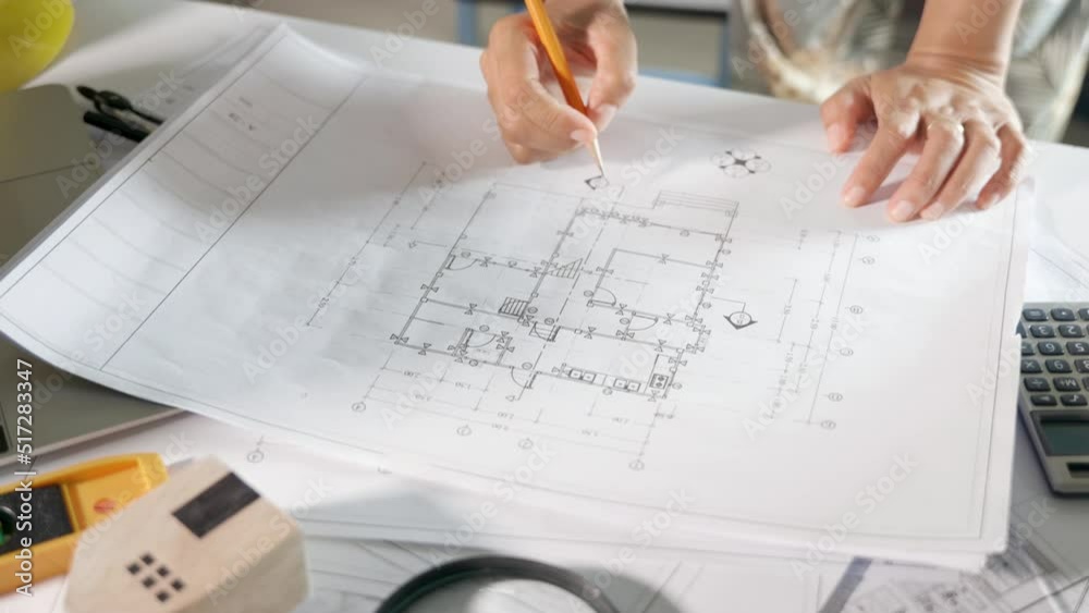 Architectural workplace. Architect open drawing paper to review and design of house editing with pencil on plan blueprint paper on table desk at architecture office, engineer sketching blueprint