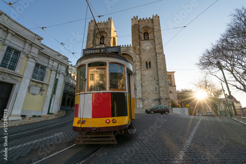 Santa Maria cathedral with blurry Tram 28 in motion. Icons of Lisbon. Portugal photo