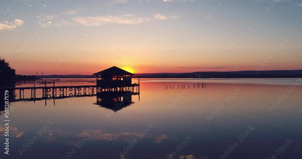Moving slowly and smoothly over a lake fishing dock and old bungalow in the sea water during beautiful sunset Moving slowly and smoothly over a lake fishing dock and old bungalow in the sea water during beautiful sunset