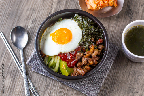 One bowl of bibimbap, korean food, serve with Seaweed soup, seaweed and Kimchi. Serve with pork and beef for add option. Food issue.