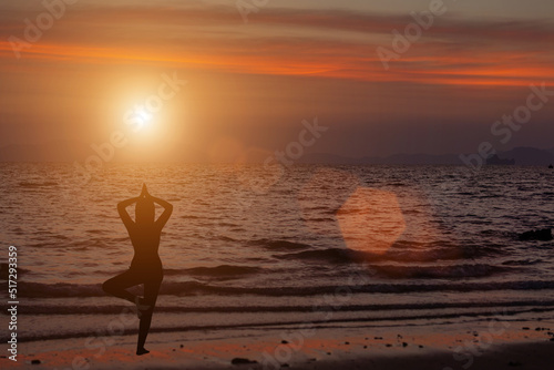 woman doing tree pose exercise when the sun goes down in the sky Concept, silhouette, love health, rest, vacation, travel