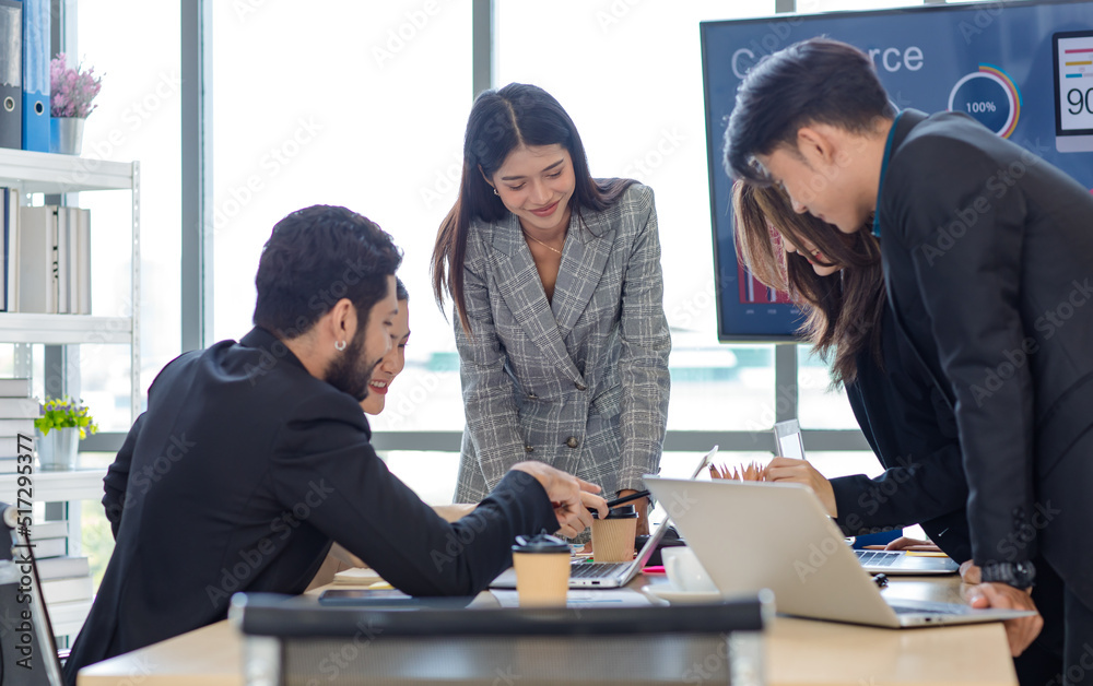 Fototapeta premium Businesswoman manager presenter in formal suit standing holding pen pointing at graph chart document on whiteboard presenting company information to Asian male female colleagues in meeting room