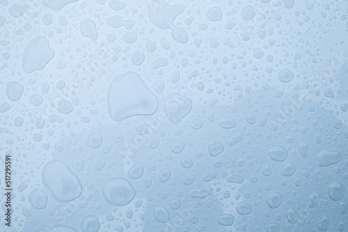 Clear water drops on transparent glass blue background 