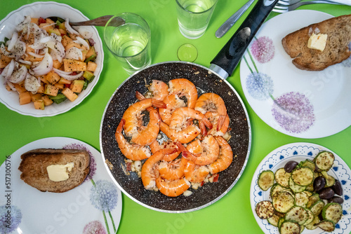 A dinner of fried shrimp with garlic, salad, bred, butter and fried zucchini.
