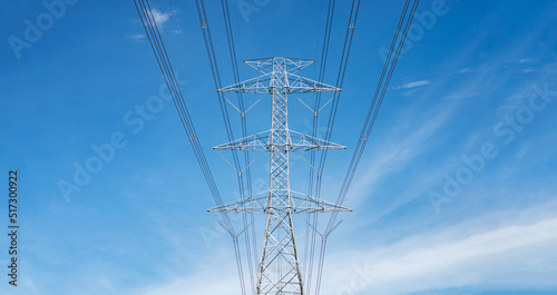 High-voltage poles and power lines contrast with the blue sky and clouds. bottom view of electric pole high voltage pole with wires
