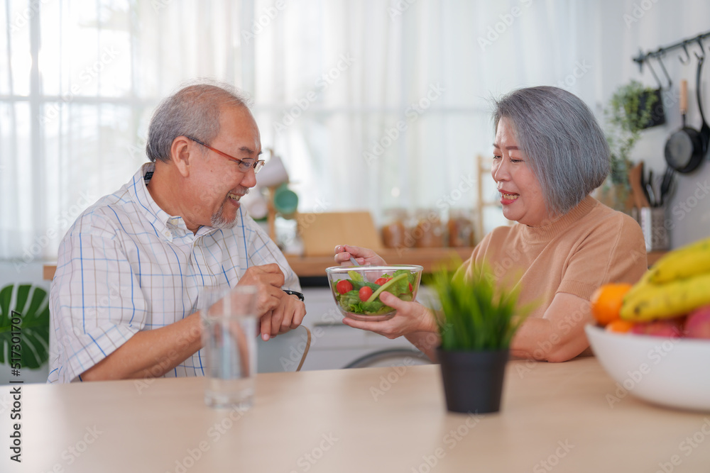 Senior couple eating salad together at the kitchen at home. Concept of healthy nutrition in older age. Senior couple eating salad together at the kitchen at home. Concept of healthy nutrition in older age.
