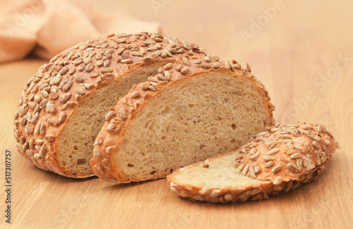 Whole fresh wheat bread with sunflower seeds and cutted off loafs or slice on the table 