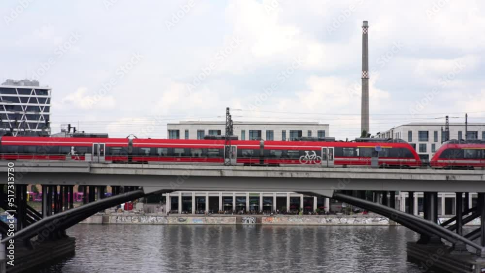 A red train drives over a bridge in Berlin.