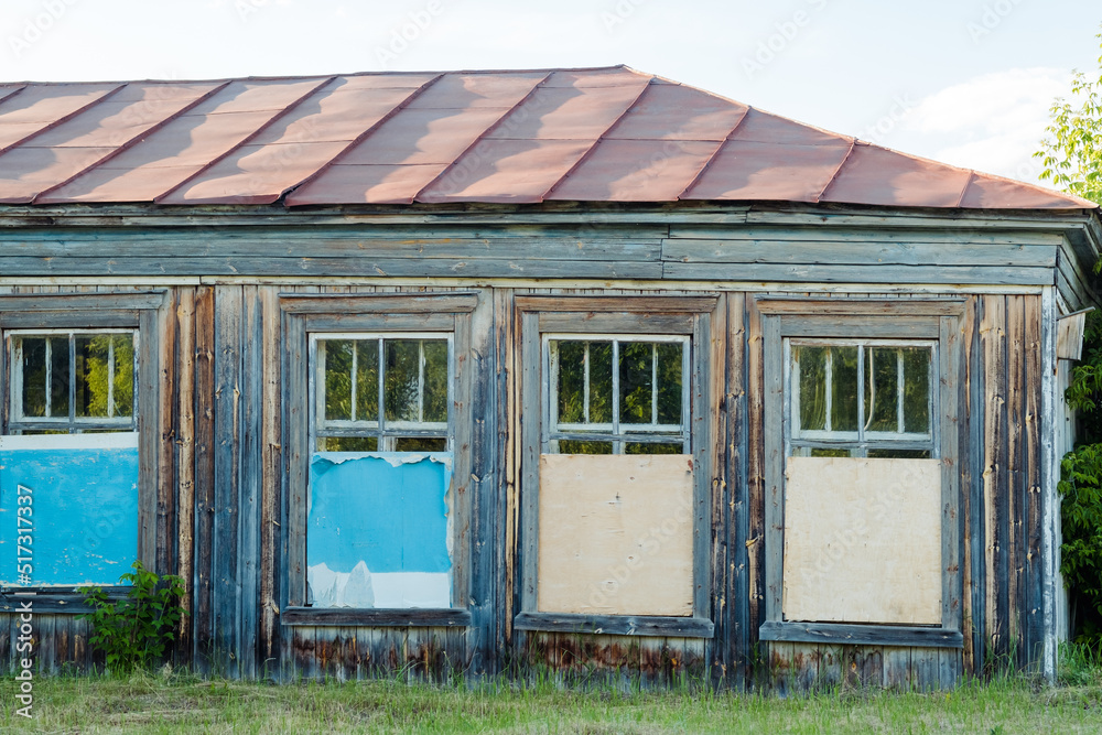 abandoned wooden house with boarded up windows in summer abandoned wooden house with boarded up windows in summer