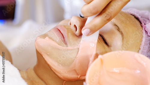 Cosmetologist applies a scrub on female face. Woman in a spa salon on cosmetic procedures for facial care.