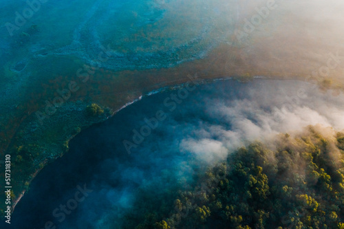 Aerial  view of a beautiful summer  landscape with a fog while dawn.  Photo from drone of a foggy landscape in spring. Top view to land while sunrise. Early morning in nature  misty  weather.