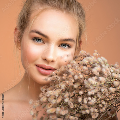 Portrait of young beautiful woman with a healthy  skin of face.  Attractive girl with a bunch spring field flowers