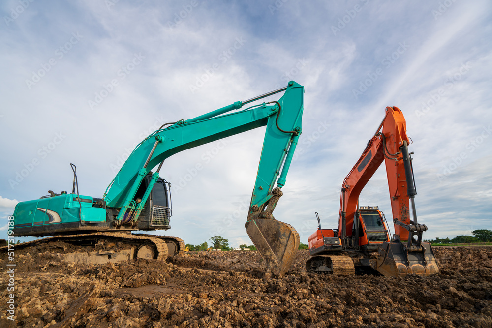 A backhoe or excavator works on a developer area into a real estate construction site A backhoe or excavator works on a developer area into a real estate construction site