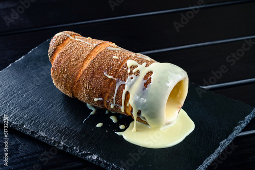 trdelnik with condensed milk filled with buttercream on a black serving tray, free space for the text photo