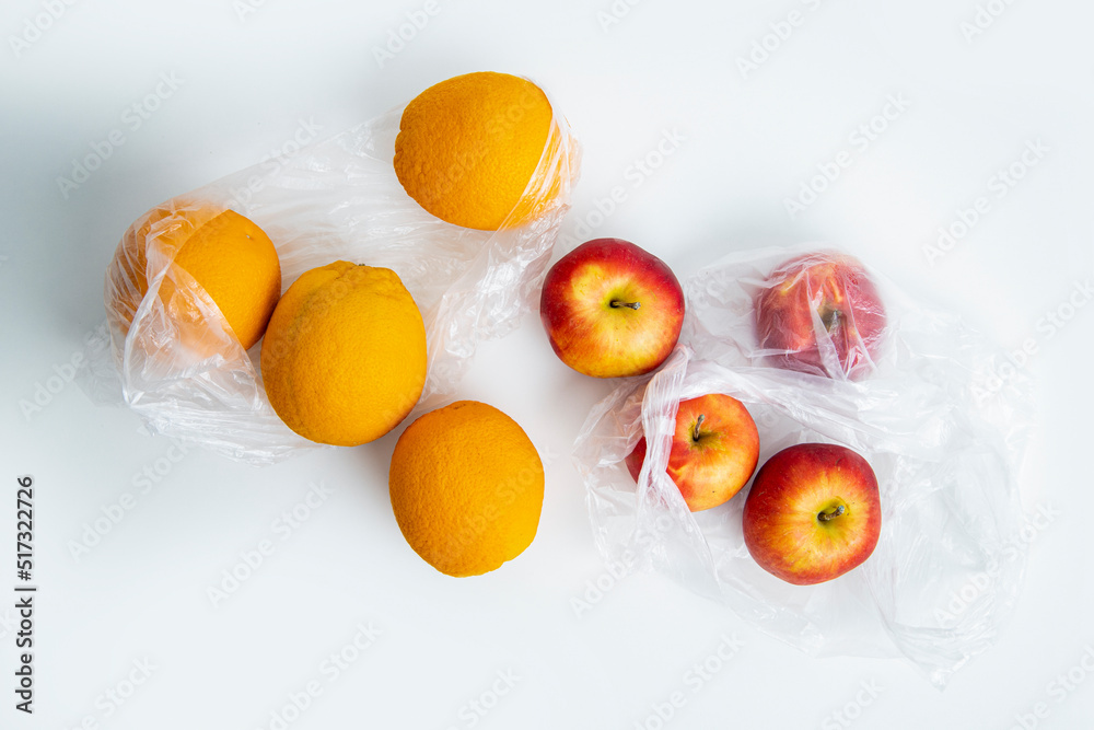 Fresh ripe oranges, apples in transparent plastic bags on a white background. Top view, flat lay Fresh ripe oranges, apples in transparent plastic bags on a white background. Top view, flat lay