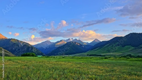 Beautiful mountain and colorful cloud nature scenery in Xinjiang at sunset, China. Green grassland with mountains nature landscape. photo