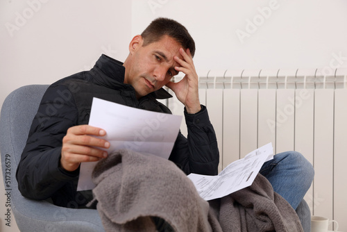 Freezing man holding bills for electricity, gas and heating. Global energy crisis concept. Cold home, Global energy crisis concept photo