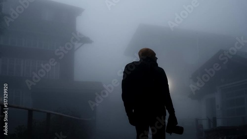Back view of a man with a backpack in a thick fog. Concept of a ghost town or a horror movie vibes.