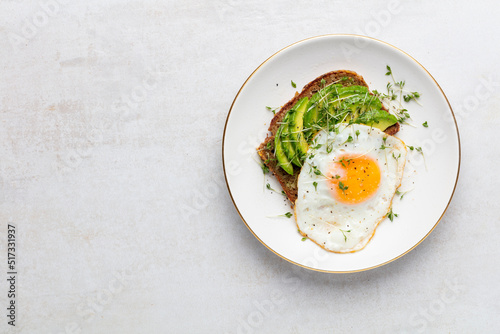 Keto breakfast fried egg, avocado and bread in a white plate. Keto diet concept.