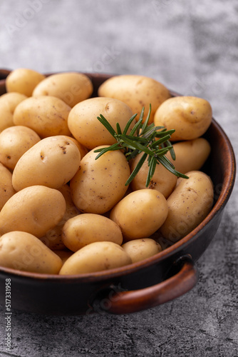 Raw small potatoes in a cast iron skillet on a beton background.
