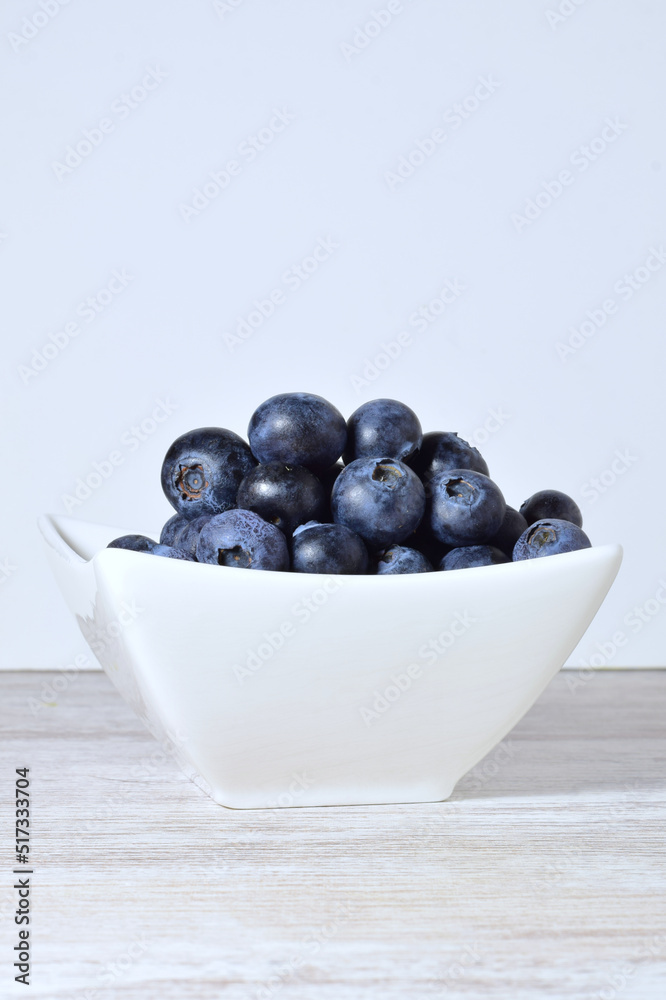 Blueberries in porcelain bowl, light background and copy space. Blueberries in porcelain bowl, light background and copy space.