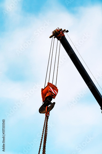 Fragment of a crane jib with a rope and a hook. The process of loading or unloading a heavy load. Vertical photo. selective focus