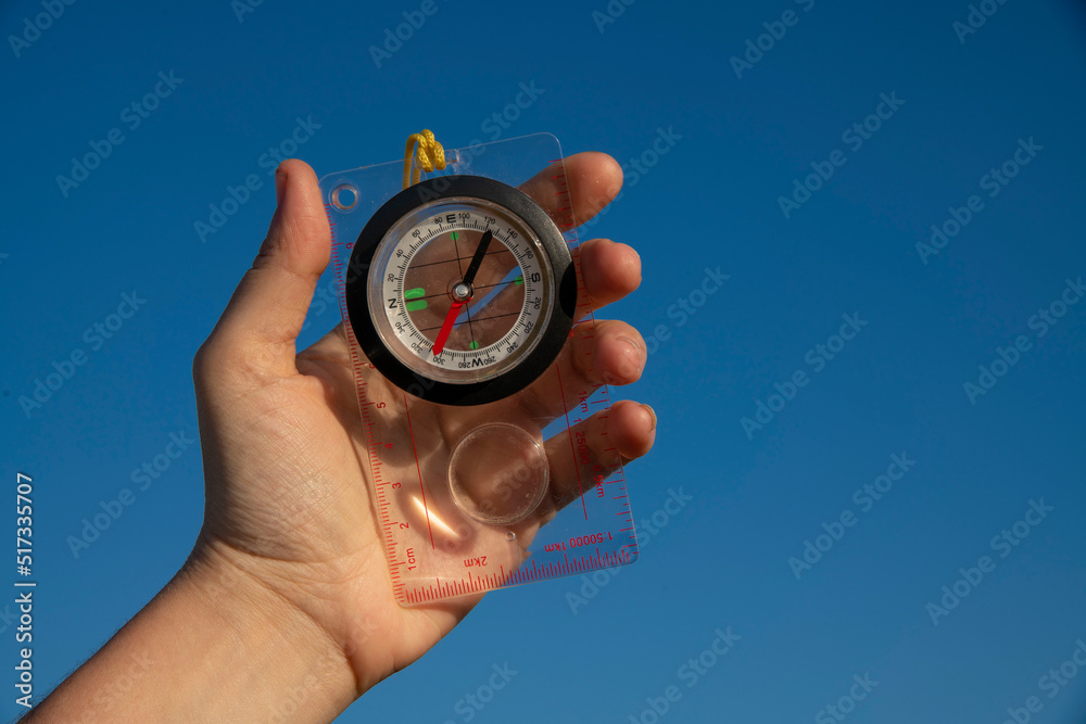 Hand holding compass on the blue sky background. Hand holding compass on the blue sky background.