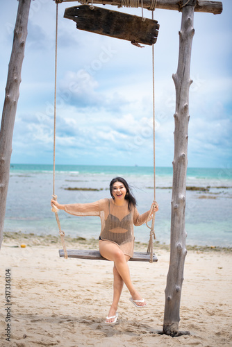 beautiful woman sitting on a swing on the beach on vacation