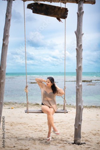 beautiful woman sitting on a swing on the beach on vacation