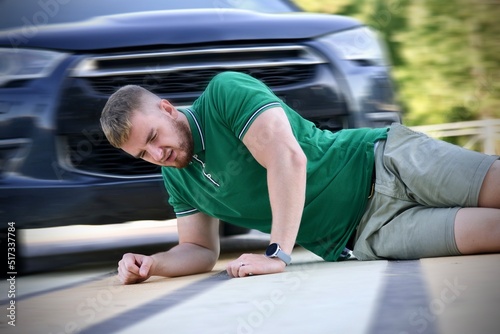 Young downed man at accident scene, crash on the road on crosswalk. Pedestrian guy hit by careless driver in a car on the road while crossing highway, person is lying on asphalt. Dangerous situation