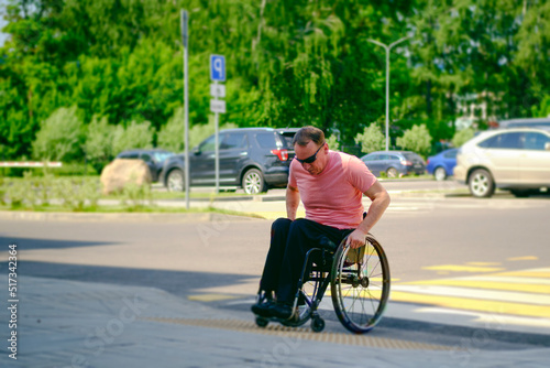 a person using a wheelchair makes efforts to move his wheelchair along a pedestrian crossing