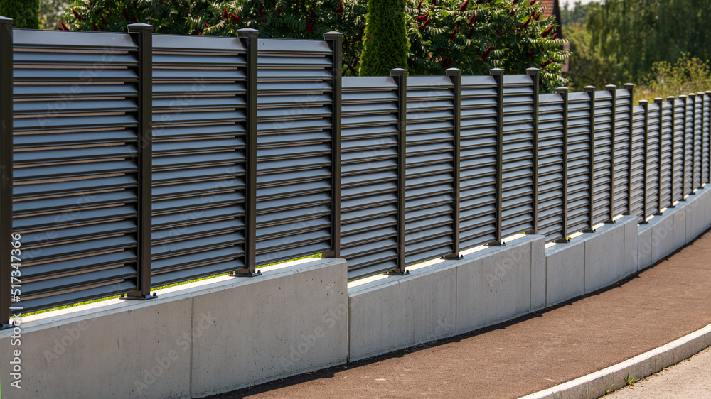Moderner Sichtschutzzaun aus Aluminium an einer Strasse mit Garten