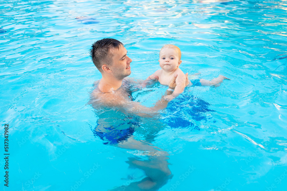 dad and baby in the pool with water slides in the summer have fun swimming, relaxing and spending time with the family on vacation or the father teaches the child to swim