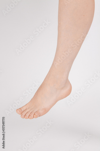Barefoot and legs isolated on white background. Closeup shot of healthy beautiful female feet. Health and beauty concept. Side view of human foot ream with neutral manicure or pedicure. Sole of foot.