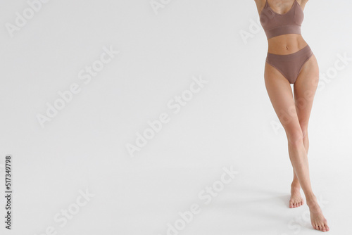Tanned slim legs of a woman on white studio background. Close up of fitness model in sports clothing. Underpants or underwear advertising. Skin care or diet banner.