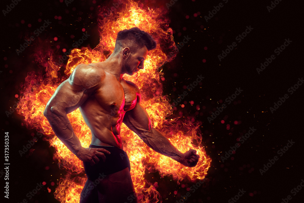 Brutal strong athletic Bodybuilder posing. Fire and spark explosion in the background.