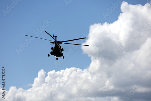 Silhouette of military helicopter Mi-8 (NATO codification: Hip) in flight on background of blue sky and white clouds