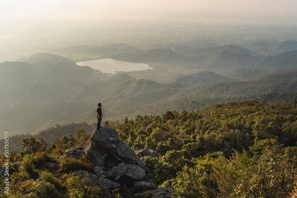 A traveling man stand on the big rock to see sunset and mountain view for relaxation