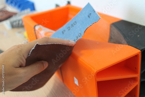 A person's hand sanding a 3d printed piece of artwork