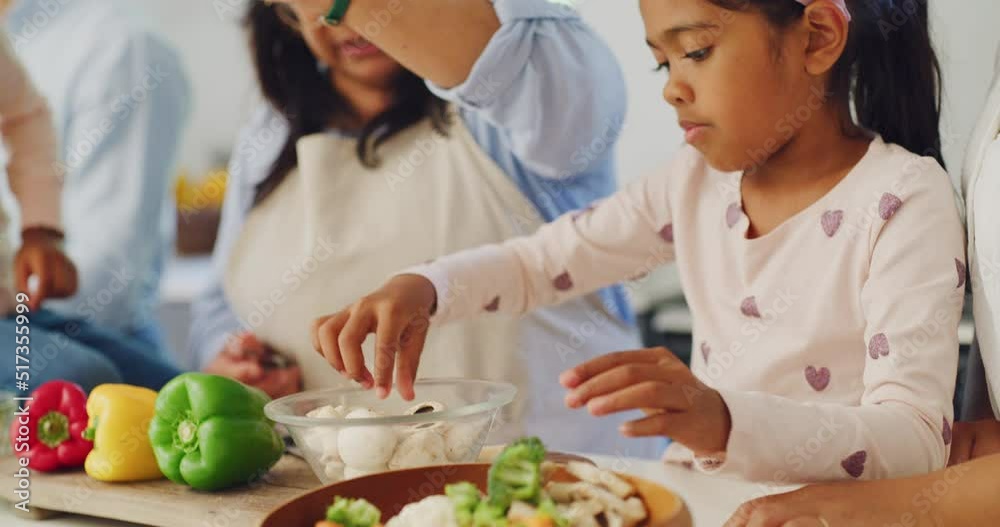 Happy family cooking dinner together in the home kitchen at home. Young girl helping her grandmother prepare a healthy meal with vegetables. Independent daughter making food with an older woman