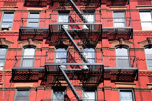 A metal fire escape on the exterior of a red brick building in manhattan in new york city.