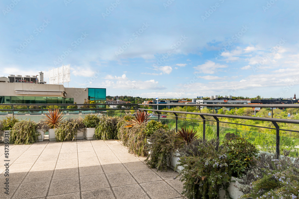 Fototapeta premium Terrace of an office building full of plants on a sunny day with some clouds