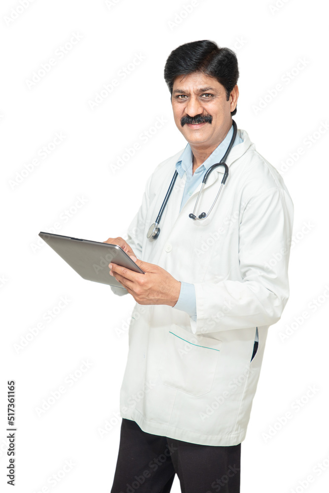 Portrait happy indian male doctor with stethoscope standing with digital tablet or notepad prescribes medicine, healthcare and medical concept. Portrait happy indian male doctor with stethoscope standing with digital tablet or notepad prescribes medicine, healthcare and medical concept.