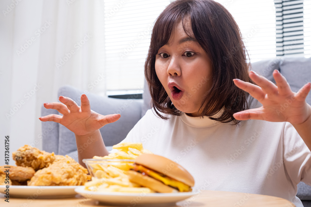 Young Asian oversize women gain weight while eating fried chicken, potato chips and French fried. Junk food that can cause obesity and unhealthy for human body. Young Asian oversize women gain weight while eating fried chicken, potato chips and French fried. Junk food that can cause obesity and unhealthy for human body.