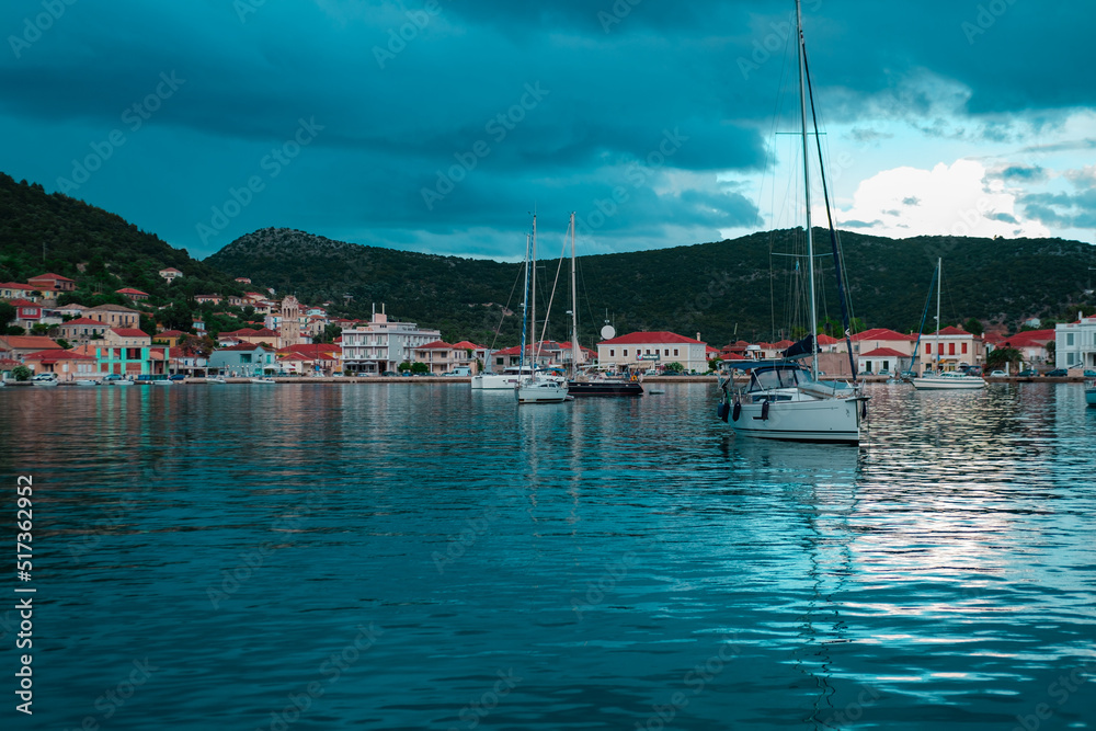 Ithaka Island, Geece - 06 june 2022 : small colorful town at sea coast, port and harbour fpr sailing boats, yachts, anchorage place, beautiful landscape at cloudy rainy twilight evening