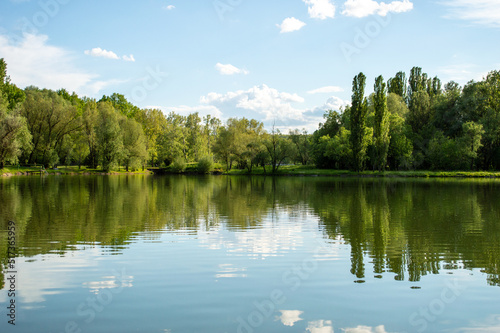 The sky is reflected in the water of the lake. In the park
