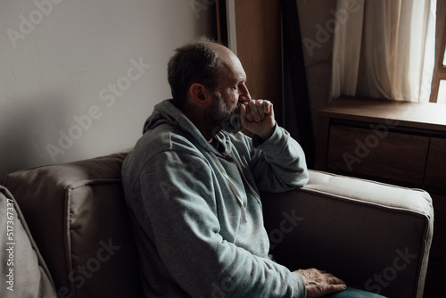Ukrainian worried middle aged man was frightened by the loud sound and closed his ears in fear. Unhappy mature older grandfather at home.