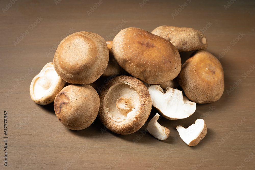 Multiple fresh shiitake mushrooms on wooden board Multiple fresh shiitake mushrooms on wooden board